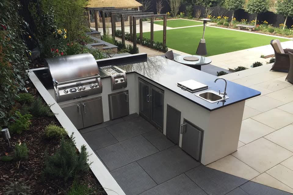 Luxury outdoor BBQ area with landscaped garden featuring Plants House Gardening's stylish plants and garden design elements.