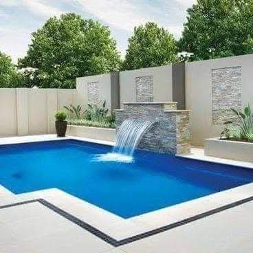 Poolside landscape with water feature and lush plants, designed by Plants House Gardening for a tranquil outdoor setting.